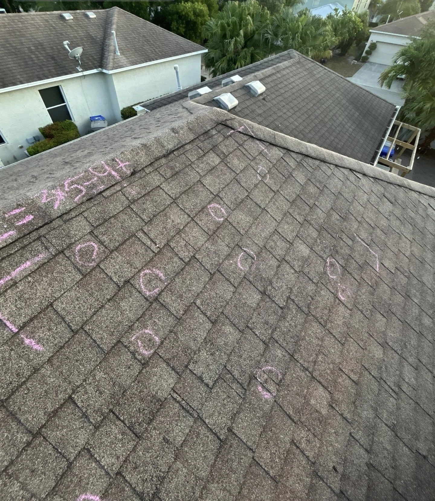 Roofing contractor assessing storm damage on a residential roof, highlighting the need for restoration services